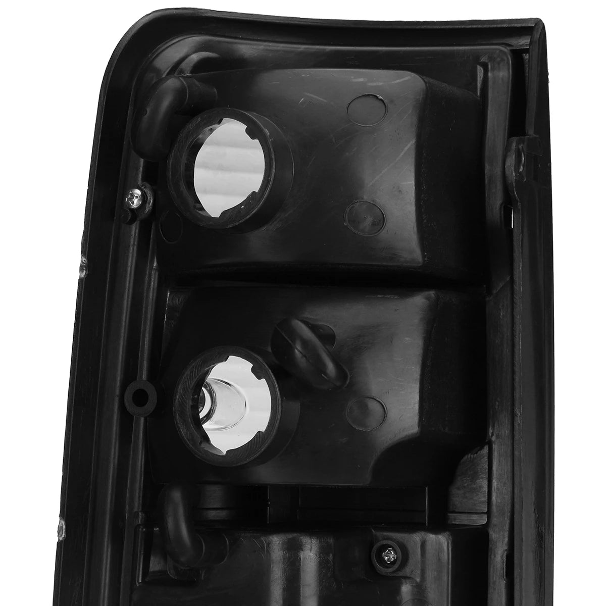A close-up view of the upper backside of a black vehicle taillight assembly, focusing on two large, circular bulb socket openings. The black plastic housing shows rubber grommets and mounting points, with reflective silver material visible inside the sockets.