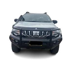 A frontal view of a white pickup truck, likely a Mitsubishi Triton, heavily modified with a large, black steel bull bar/bumper replacement. The bull bar features a main hoop covering the grille and headlights, and includes integrated fog lights and turn signals. The vehicle is presented against a checkered, transparent background.
