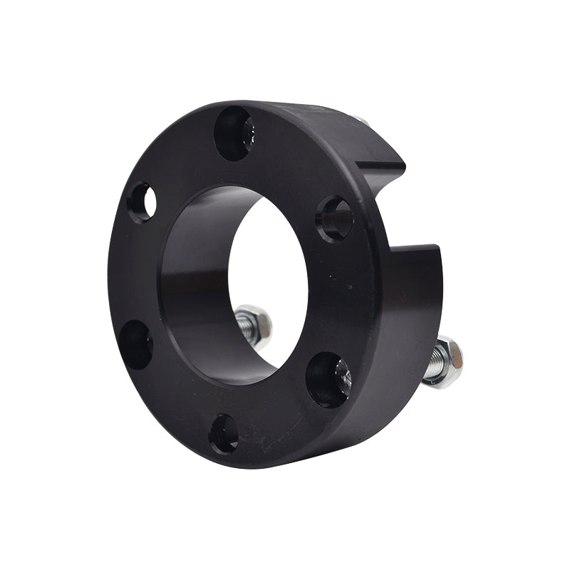 A close-up of a single black, round metal spacer likely for a vehicle's suspension system, such as a strut spacer for a lift kit. The spacer has a large central opening, five smaller bolt holes around the circumference, and a notch or cutout on the side. Two silver bolts with nuts are partially inserted into the side of the spacer. The object is shown against a white background.