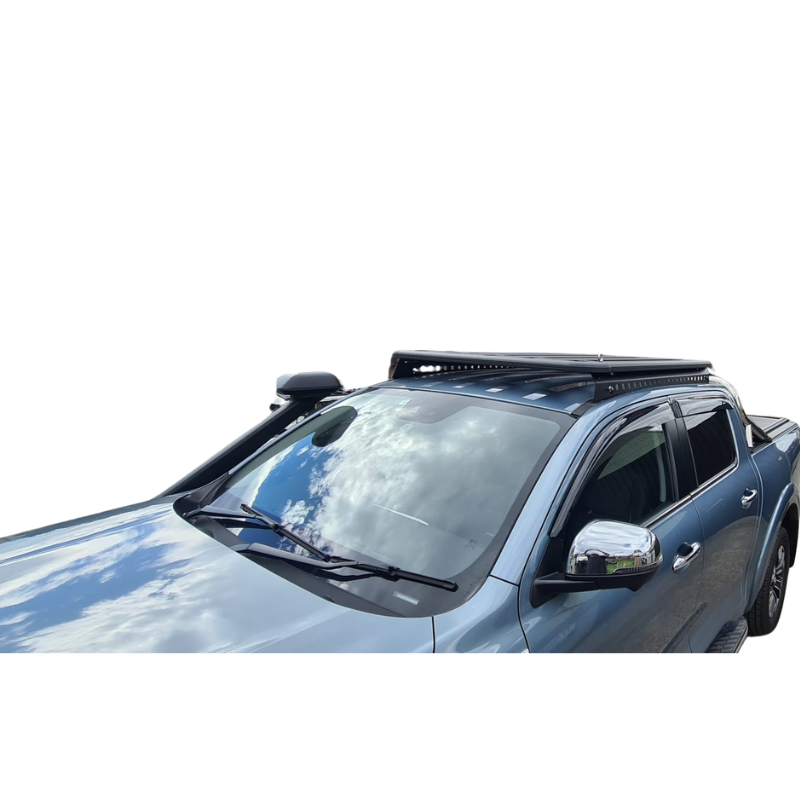 A high-angle photo showing the front section of a light blue pickup truck, possibly a Nissan Navara. The truck is fitted with two aftermarket accessories: a black snorkel running up the passenger side A-pillar and a low-profile, black platform roof rack mounted over the cab. The sky with white clouds is reflected on the truck's windshield and hood.