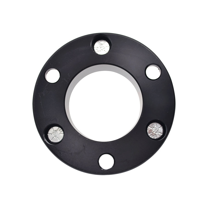 A flat, black, round metal spacer with a large central hole. It has five smaller outer holes, two of which contain silver bolts that sit flush with the surface. This component is likely a wheel spacer or suspension spacer for a vehicle.