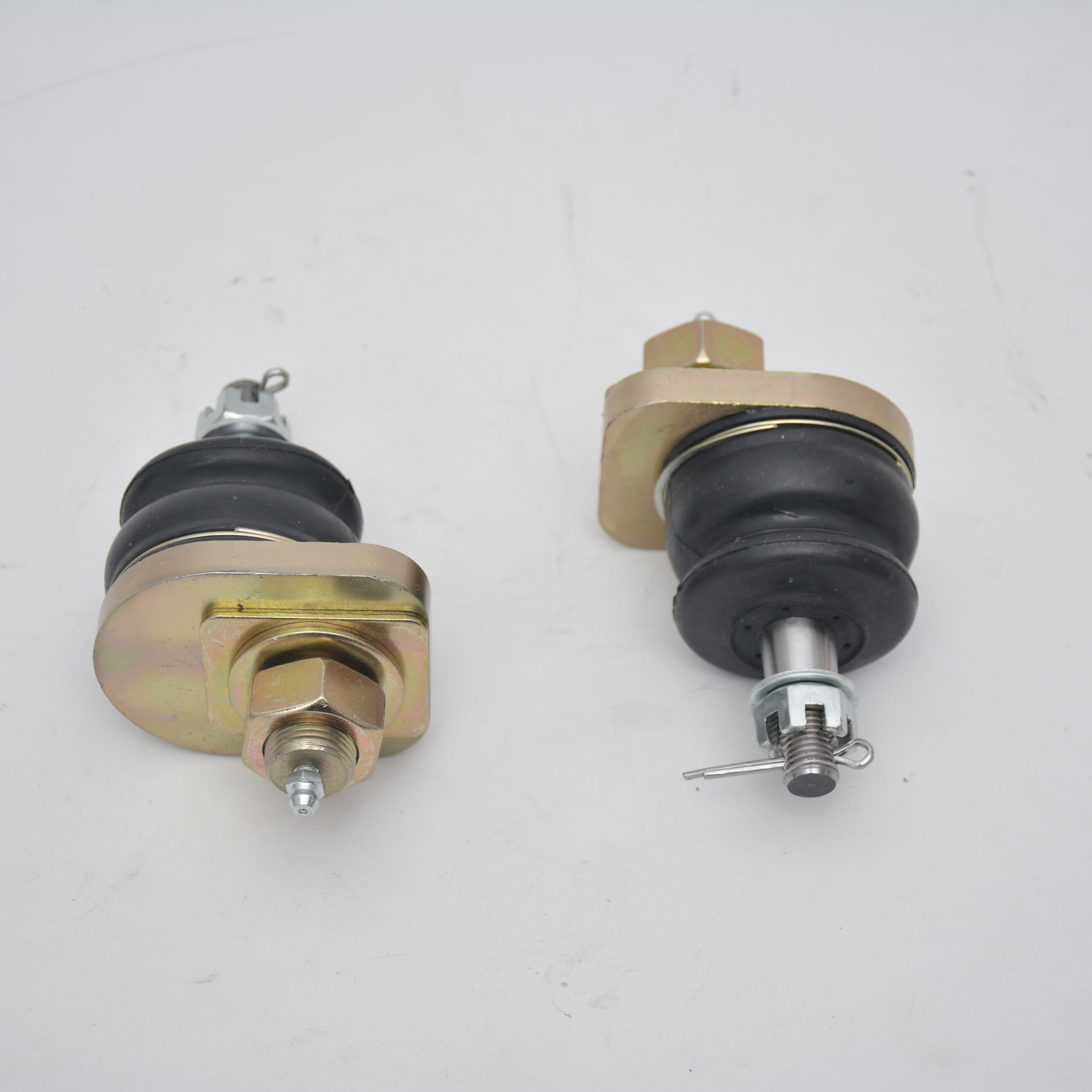 A pair of heavy-duty, gold-plated automotive ball joints, complete with black rubber dust boots and hardware including nuts and cotter pins.