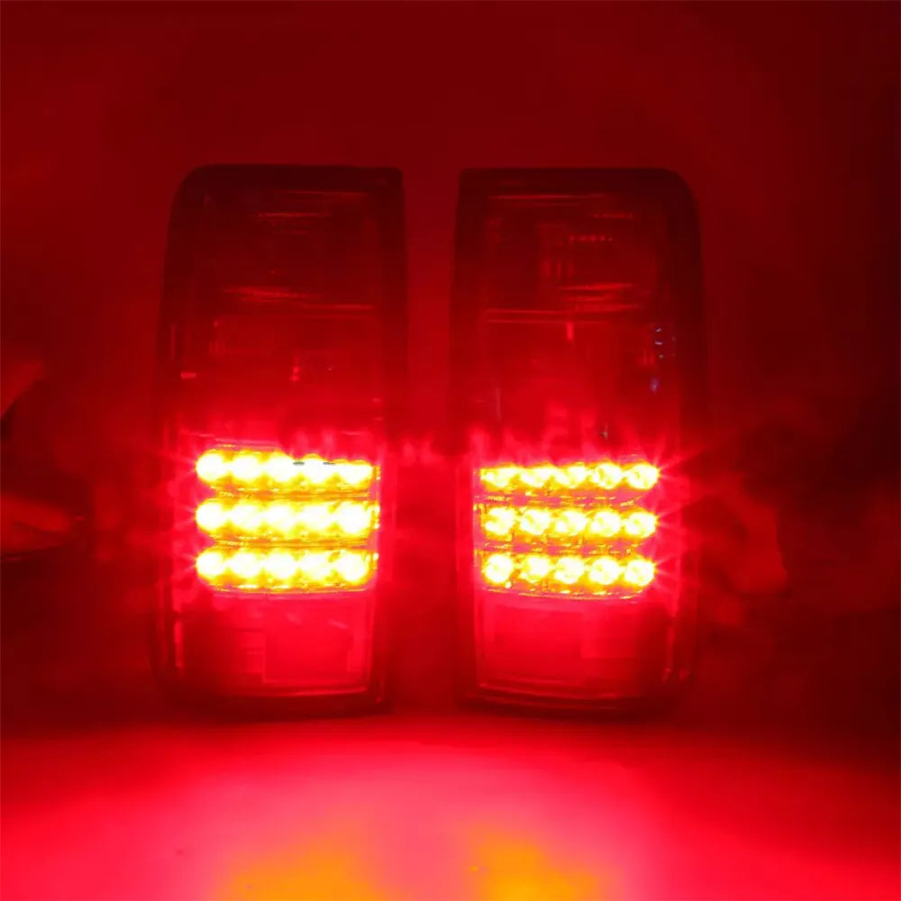 A pair of vertical LED taillights illuminated in a dark setting, showing the bright, intense red glow of the lower LED sections. Each light has approximately three horizontal rows of glowing red LEDs, making the light visible and prominent against the dark background.