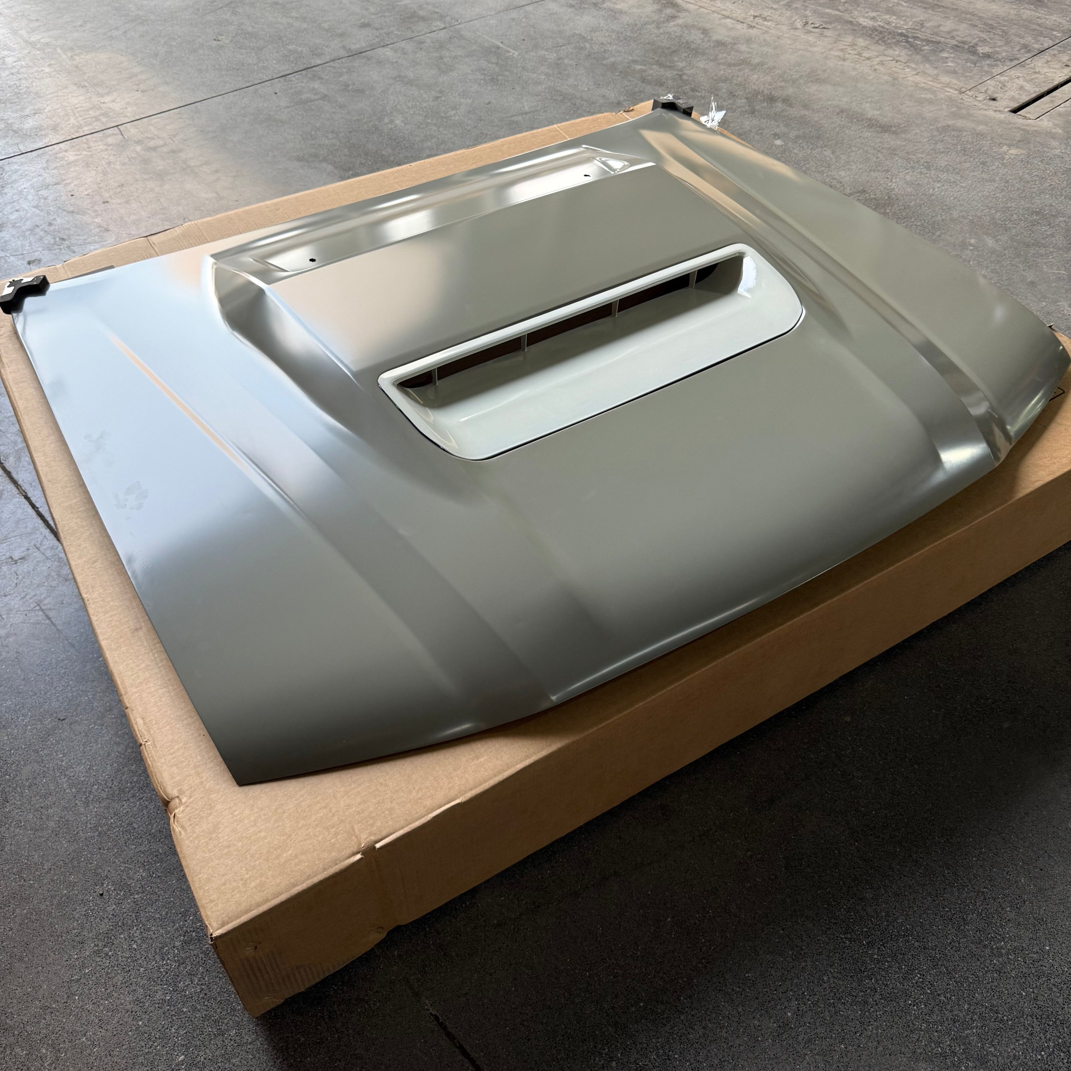 Metallic car hood on a cardboard box outdoors