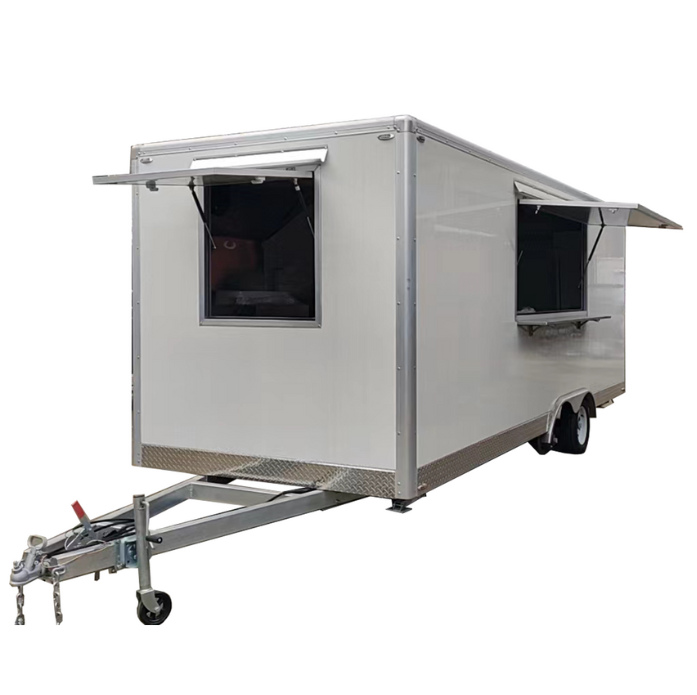 A white rectangular food trailer with silver trim. It has two service windows open on the side, and a hitch assembly at the front for towing. The trailer is dual-axle and appears to be new or well-maintained, photographed against a white background.