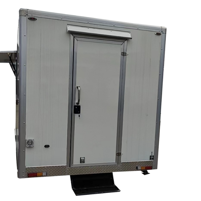 The rear view of a white rectangular food or cargo trailer, showing the main entry door. The door is centered on the back panel, featuring a handle, lock, and a small awning or cover above it. The bottom of the trailer has a diamond-plate metal accent, taillights, and a small black step.