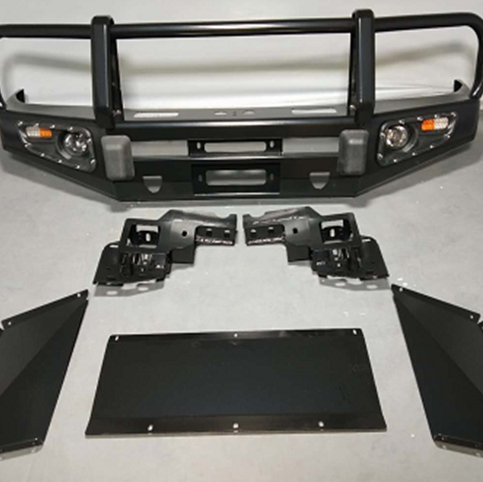 A comprehensive kit of black, heavy-duty off-road vehicle armor laid out on a gray surface. The kit includes a large steel bull bar with integrated lights and a winch opening, two mounting brackets, and three pieces of black skid plate/underbody protection (one central plate and two angled side plates).