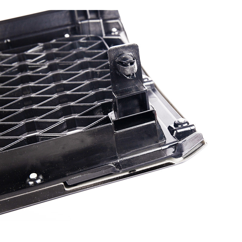 A close-up photo showing the black plastic construction and mounting points on the back of a vehicle grille or grille insert. The design features a geometric honeycomb or lattice pattern, and a specific clip or mounting bracket is prominently visible in the foreground. The item is isolated on a white background.