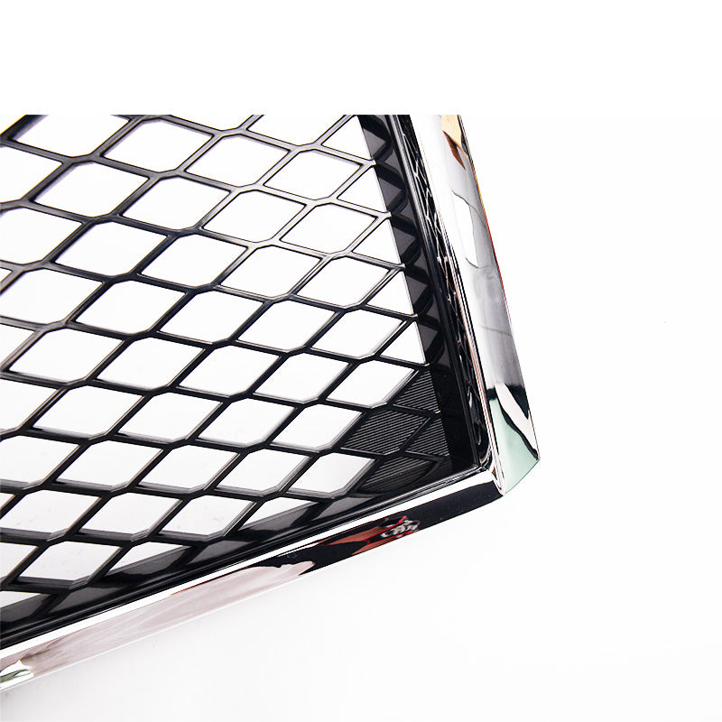 A detailed close-up of the corner of a vehicle grille insert. The frame is a highly reflective chrome or polished silver material, surrounding a center insert with a distinct, open black diamond mesh pattern. The item is isolated against a white background.