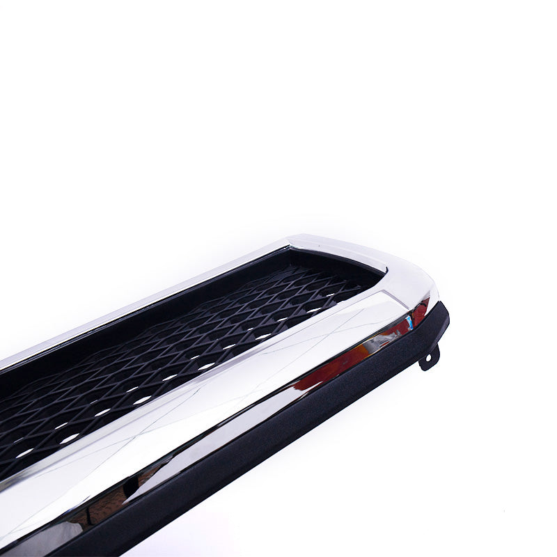 A close-up, angled view of a rectangular vehicle grille insert. The piece features a highly reflective chrome or polished metal trim and a recessed section with a black diamond-pattern mesh insert. The item is shown against a bright white background.