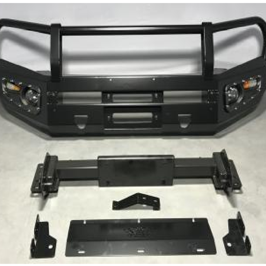 A matte black heavy-duty aftermarket front bumper, likely a bull bar or grille guard style, designed for a truck or SUV. The main bumper assembly features integrated light housings on either side, a horizontal bar across the top, vertical supports, and an opening/mount point in the center for a winch or license plate. Below the main bumper assembly are various mounting brackets, a winch cradle/mount, and a skid plate, all separated and laid out on the ground, showing a complete kit.