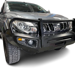 A close-up, front-quarter view of a gray pickup truck, likely a Mitsubishi Triton, focusing on its off-road modifications. It features a heavy-duty black steel bull bar or bumper replacement with a central hoop, integrated fog lights and turn signals, and a rugged, knobby off-road tire visible on the left. The truck is set against a checkered, transparent background.