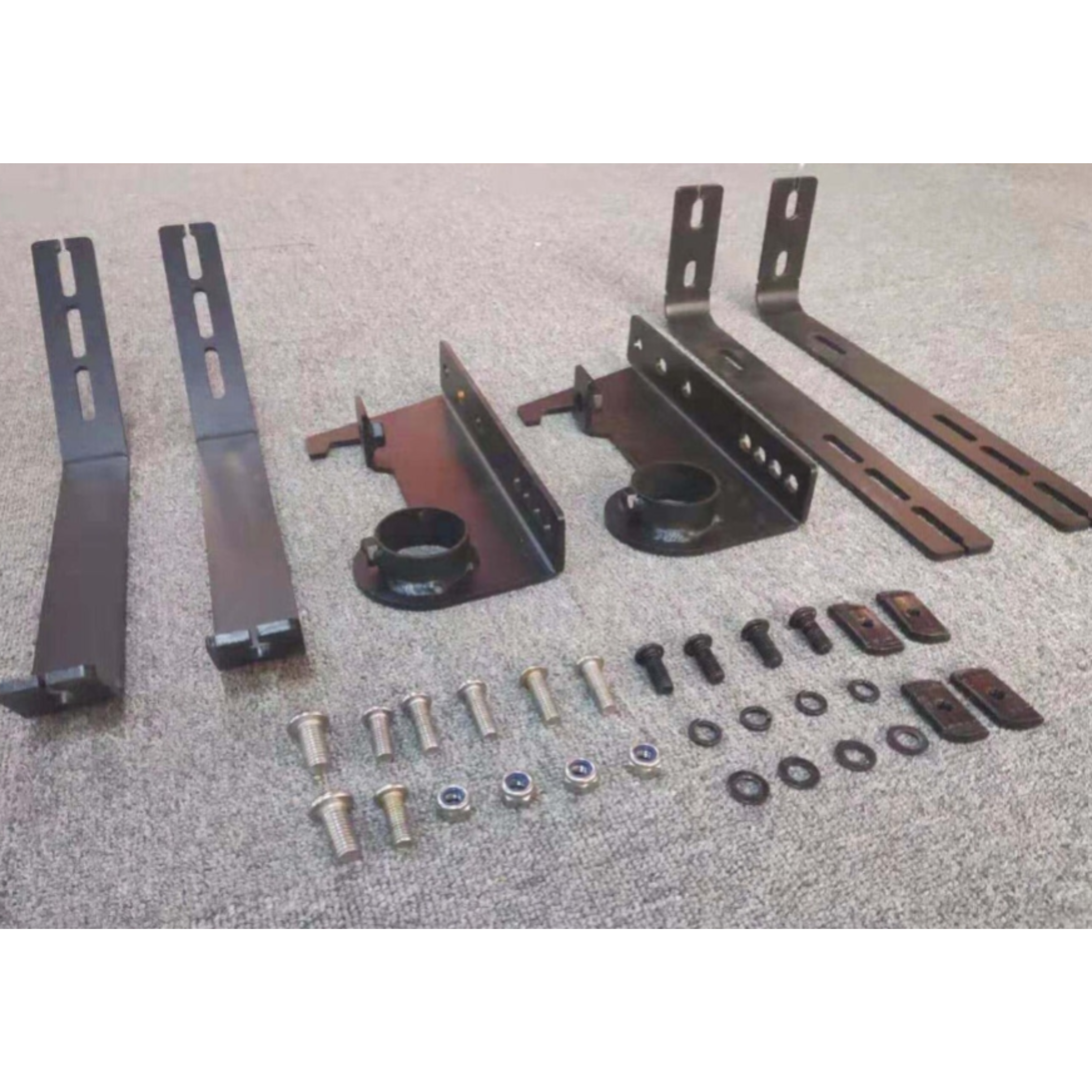 A disassembled kit of black metal brackets and assorted hardware (bolts, nuts, and washers) for mounting an accessory, likely a roof rack or light bar, displayed on a grey carpeted surface. The kit includes two pairs of long, slotted L-shaped brackets, two central mounting plates with welded collars, and an array of silver and black fasteners.