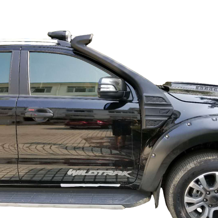 A close-up, side-view photograph of a black pickup truck (specifically a Ford Ranger Wildtrak, indicated by the decal near the bottom). The truck is fitted with a black snorkel running up the A-pillar and fender. It also features black fender flares with visible bolts and a silver and black side step. The background is a mix of a building reflection in the window and a digital checkered pattern.
