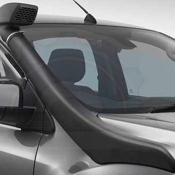 A close-up shot focusing on the black automotive snorkel installed on the passenger side of a silver or light grey pickup truck. The snorkel runs along the fender and up the A-pillar, secured by a metal band/clamp near the top. The square snorkel head/air ram is visible above the windshield, featuring a honeycomb or mesh grille intake. A whip antenna is also visible on the roof.