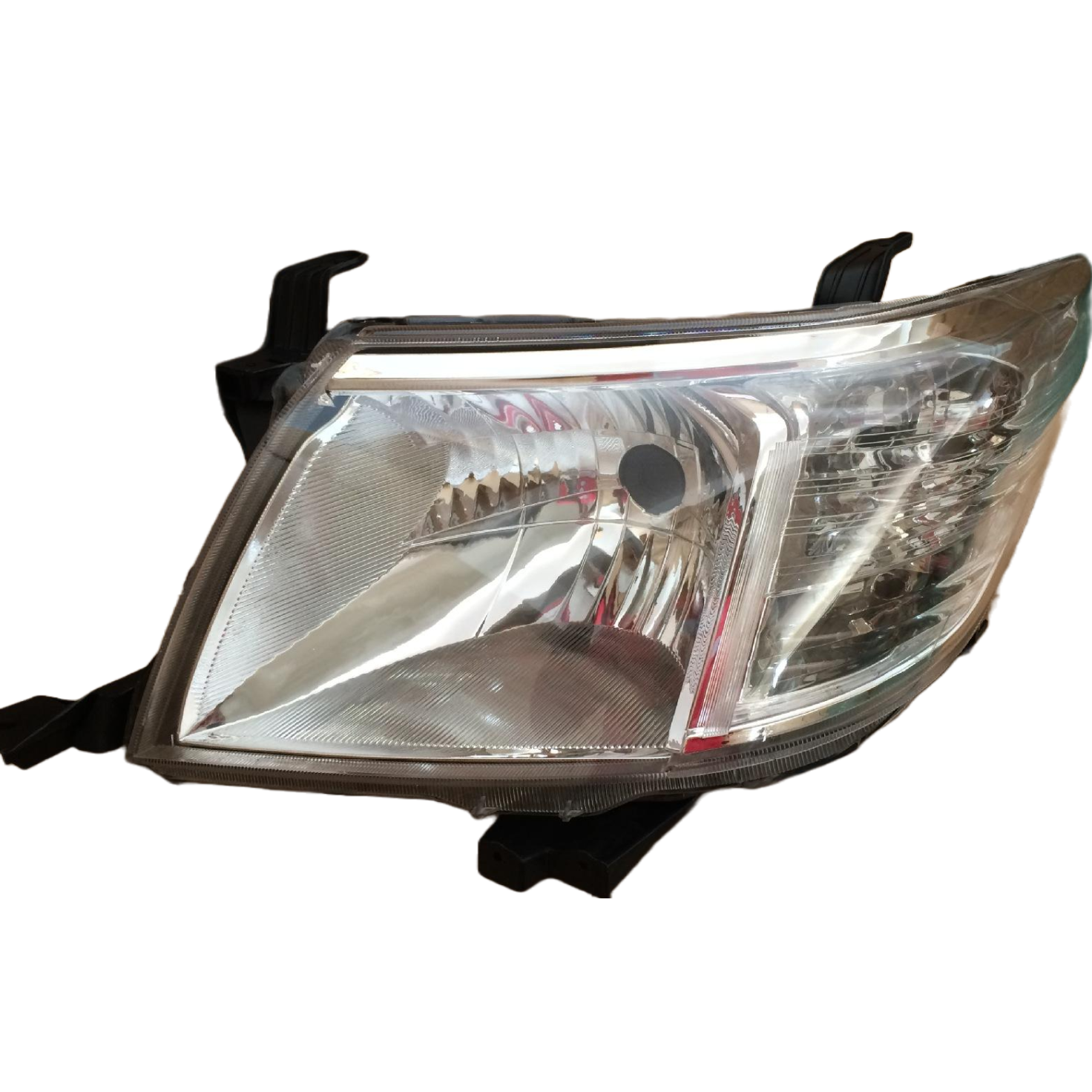 A photograph of a single, clear automotive headlight assembly for a vehicle like a truck or SUV, isolated on a white background. The headlight features a transparent plastic lens covering a reflective interior divided into sections for the high/low beam and indicator light. Black mounting tabs are visible extending from the top and bottom of the unit.