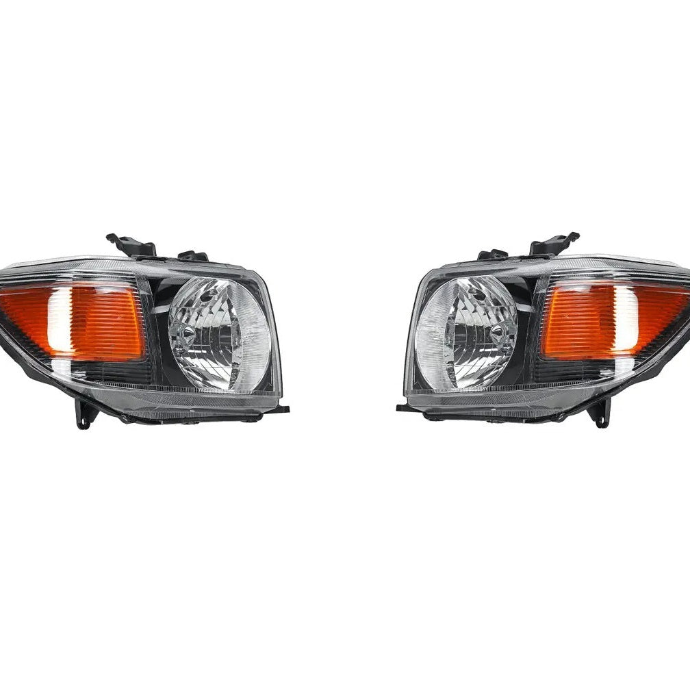 A side-by-side product image showing a pair of new, clear lens headlight assemblies for a vehicle, isolated on a white background. Both units feature a black housing, a large clear lens over the main reflector beam, and a prominent amber corner reflector or turn signal lens.